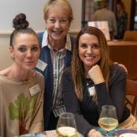 Three women at event, smiling for camera